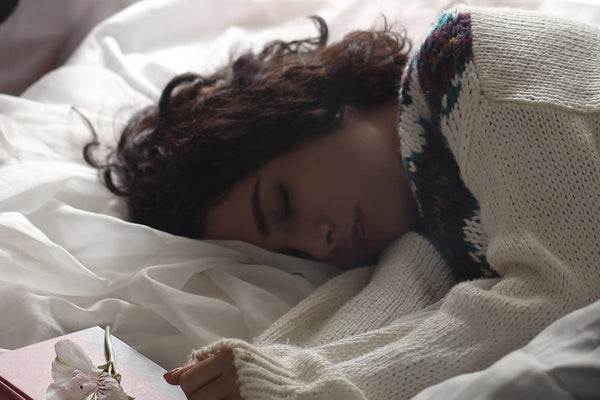 A woman asleep in bed beside an open book