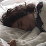 A woman asleep in bed beside an open book