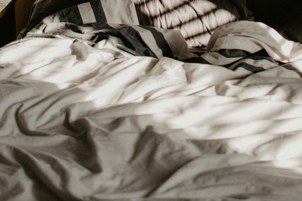 Morning sunlight falling across a bed in a quiet bedroom