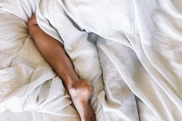 A person resting in bed under a soft white blanket