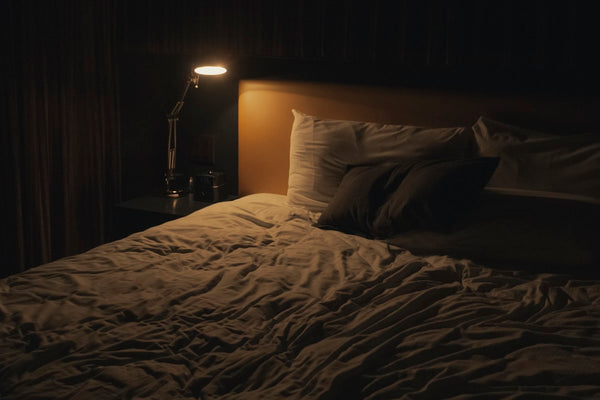 A bedside lamp switched on in a dark bedroom at night