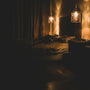 A dimly lit, cosy bedroom at night with warm lamp glow and soft white linen — the calm setting of a sleepmaxxing routine.