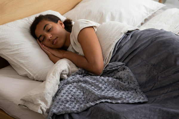 A woman resting in bed under a grey blanket with her head on a pillow