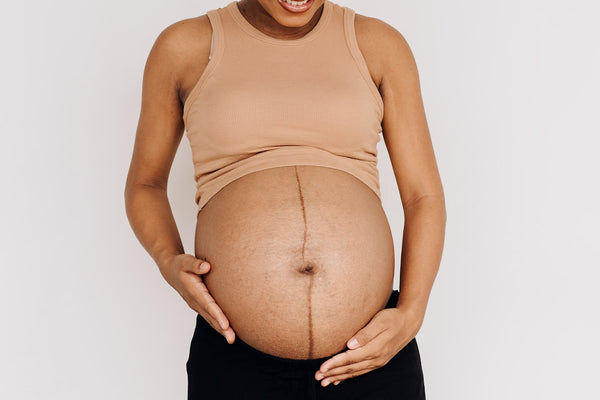 A calm portrait of a pregnant woman resting with her hands on her belly