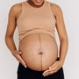 A calm portrait of a pregnant woman resting with her hands on her belly