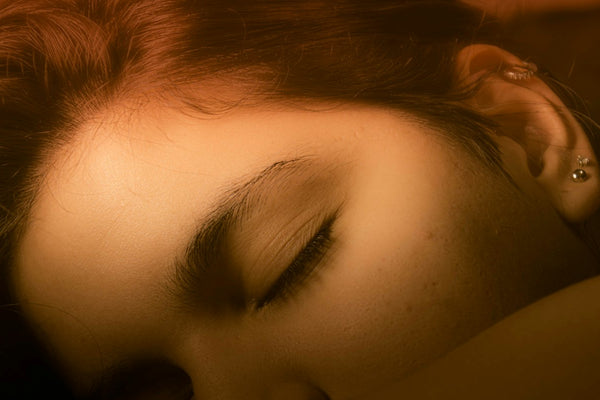 A woman asleep with warm lamp light falling across her face