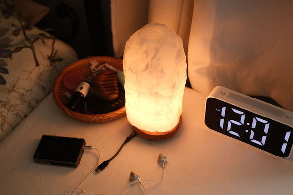 A warmly lit bedside table with a lamp and clock at night