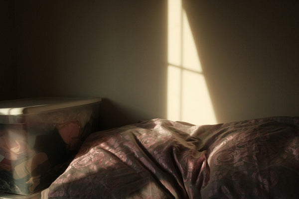 A person sleeping peacefully under a duvet in a calm, dimly lit bedroom