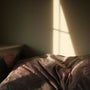 A person sleeping peacefully under a duvet in a calm, dimly lit bedroom
