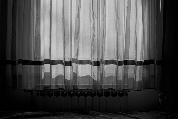 Soft morning sunlight streaming through sheer curtains onto a calmly made white-linen bed — a peaceful, considered context for thinking about mouth taping and sleep apnoea.