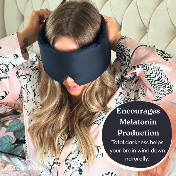 Woman wearing a black sleep mask with text about melatonin production.