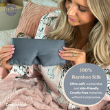Woman holding a gray bamboo silk mask with product details on a blurred background