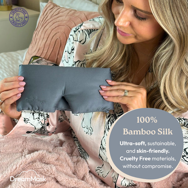 Woman holding a gray bamboo silk mask with product details on a blurred background