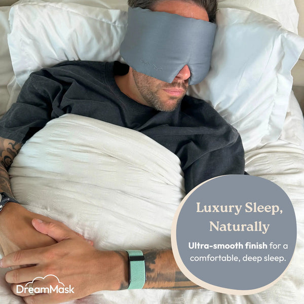 Person wearing a gray sleep mask in bed with promotional text for DreamMask.