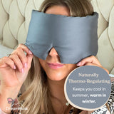 Woman wearing a gray sleep mask with text about its thermoregulating properties.