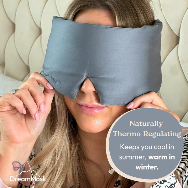 Woman wearing a gray sleep mask with text about its thermoregulating properties.