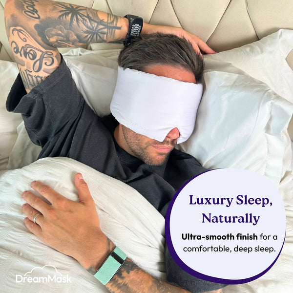 Man wearing a white sleep mask lying in bed with text about luxury sleep.