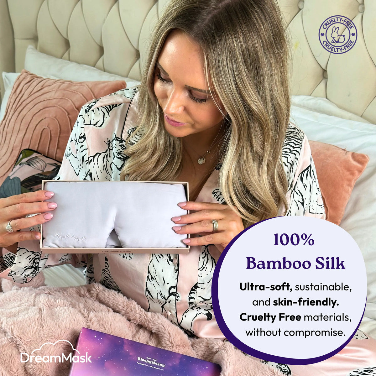 Woman holding a box of DreamMask bamboo silk product in bed