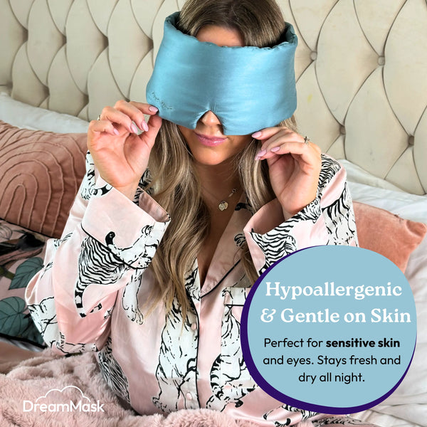Woman wearing a blue sleep mask with promotional text about its hypoallergenic and gentle properties.