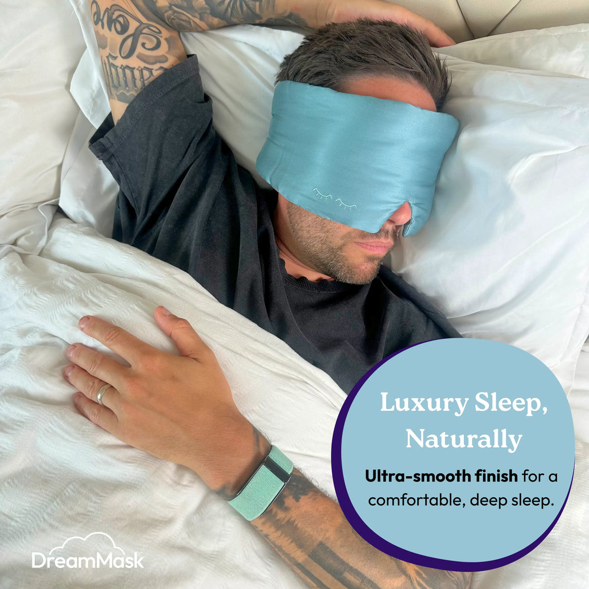 Person wearing a blue sleep mask in bed with 'DreamMask' branding.