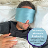 Person wearing a blue sleep mask in bed with text about melatonin production.